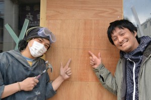 杉浦さん（右）と、自転車日本一周の旅の途中で工事を手伝った伊藤誠さん。改装工事中の建物の前で。