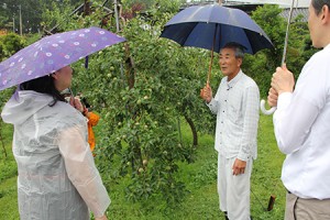 樋ノ田果樹園にてパソナグループ役員のみなさんに説明をするりんご農家の熊谷賢一さん