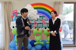 開会の挨拶のあと、今日の出店者の紹介をする佐藤代表（左）と、ガーデンカフェ地蔵庵オーナー高原あかねさん（右）。BalloonArt Nod制作のバルーンアートは「カエルがかわいい」と子どもたちに人気だった